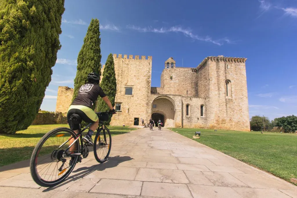 Cyclist riding toward the historic Flor da Rosa Monastery in Alentejo, Portugal