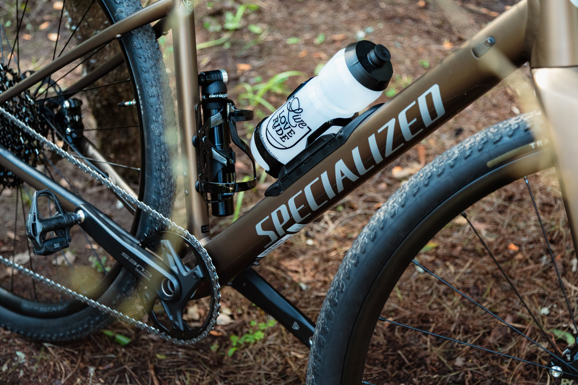 Close-up of Specialized Diverge Sport Alloy gravel bike frame with Shimano CUES drivetrain and bottle on forest trail